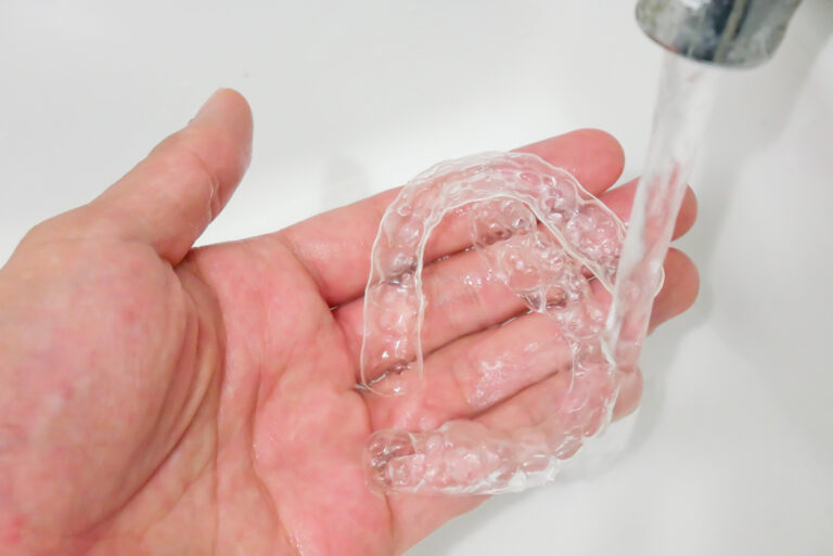 Hand Holding Clear Plastic Retainer Teeth