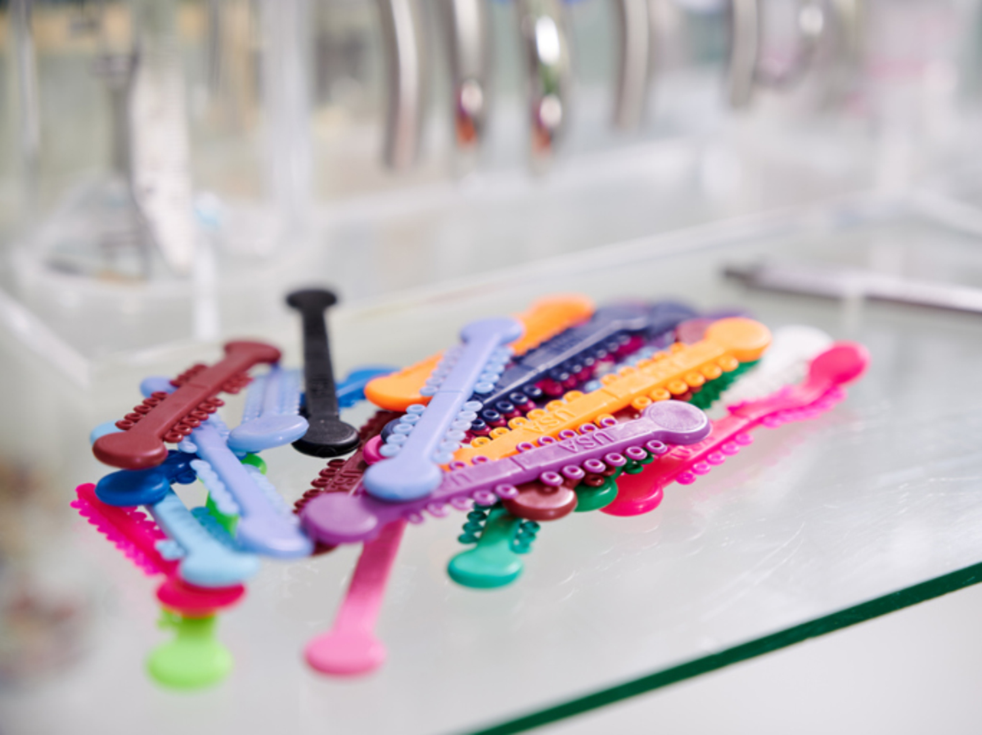 Assortment of different colored braces rubber bands on a glass surface