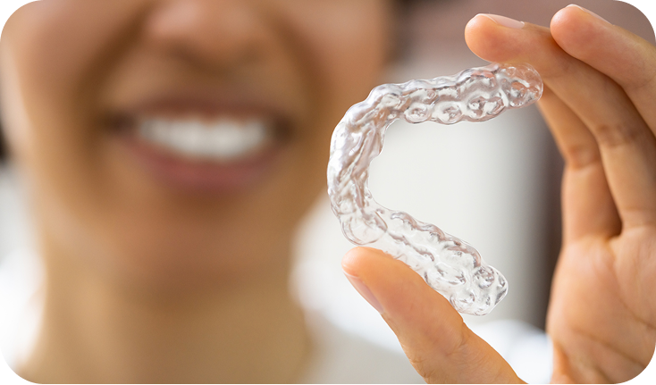 Close up of a clear aligner being held by a woman