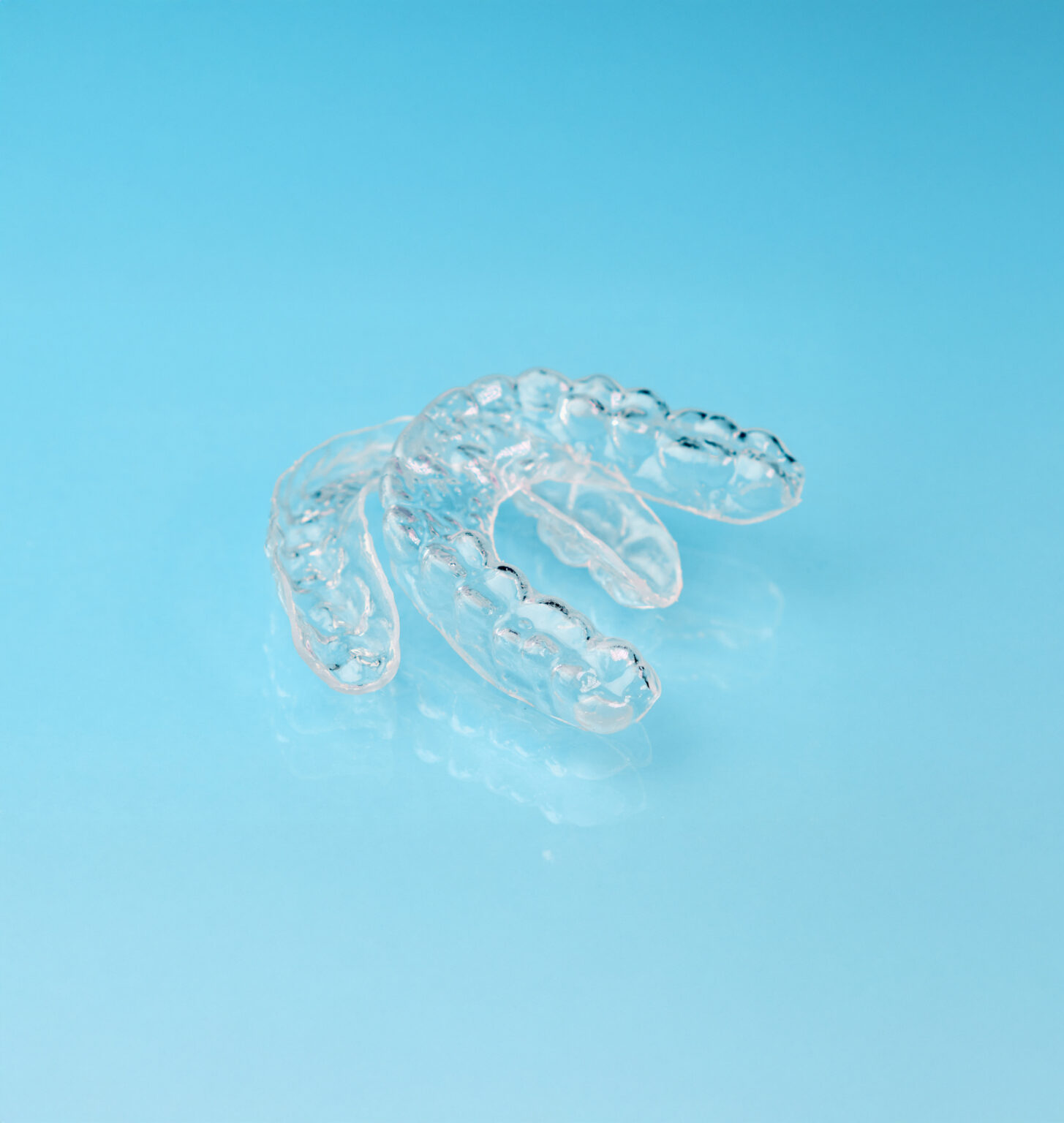 Removable aligners on the blue background with copy space. Orthodontic treatment for beautiful smile